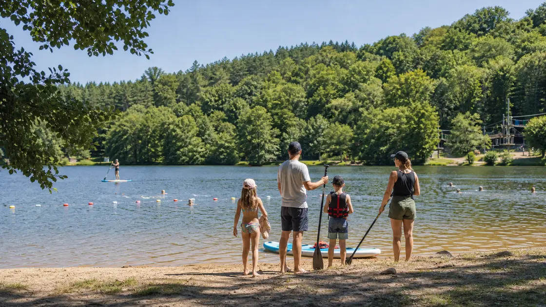 Une famille prépare une sortie en paddle au bord d'un lac entouré de forêt