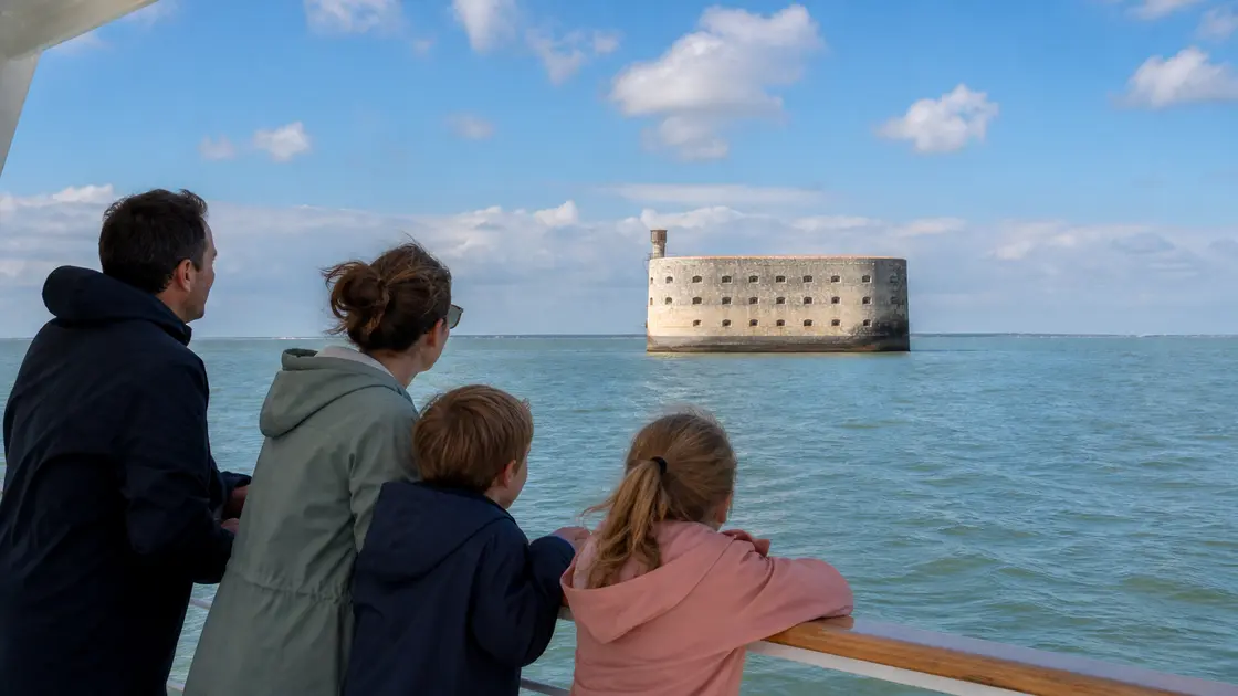 Une famille regarde Fort Boyard depuis le pont d’un bateau de promenade