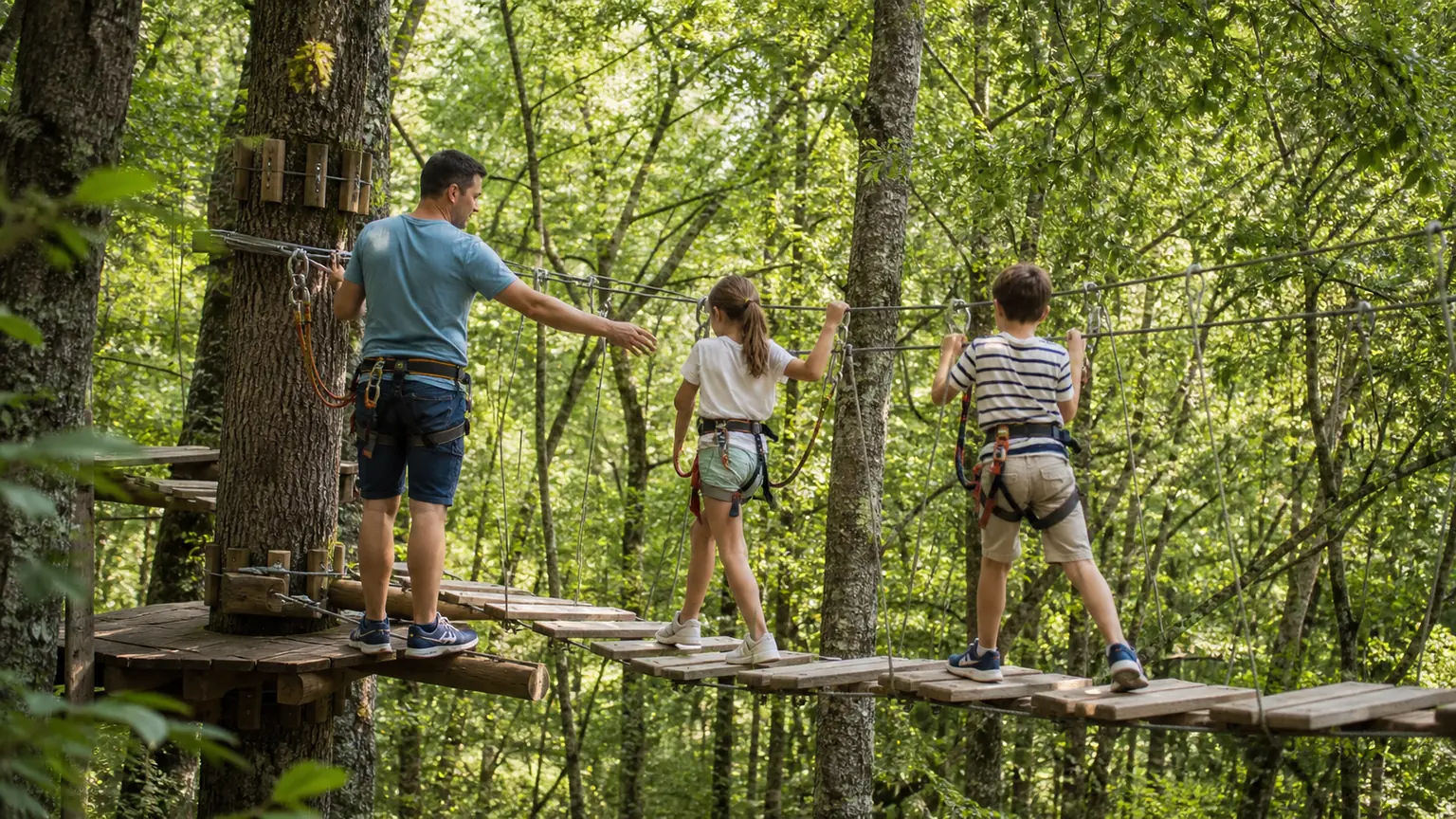 Une famille profite d'un parcours accrobranche en forêt au Parc Family Aventure
