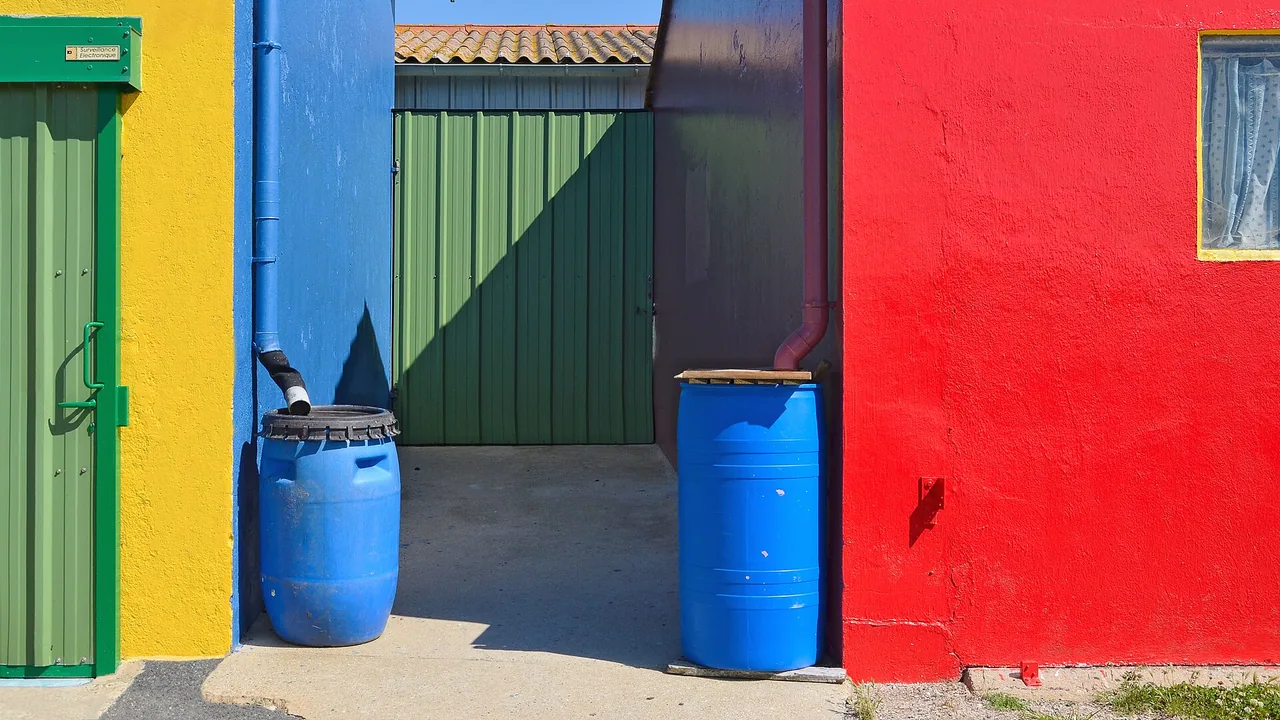 Plusieurs bidons colorés utilisés comme récupérateurs d’eau de pluie