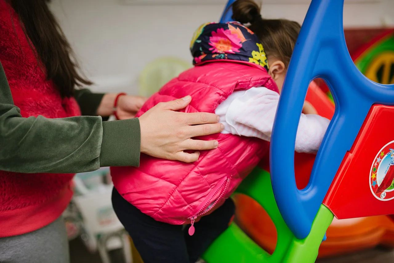 Jeune enfant jouant dans un espace intérieur avec un adulte à ses côtés