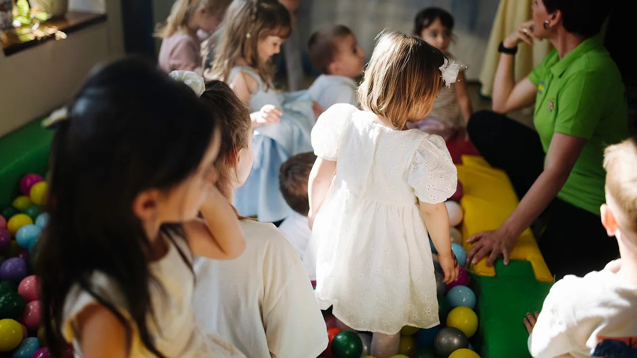 Jeunes enfants jouant avec un adulte dans un espace intérieur adapté à la petite enfance