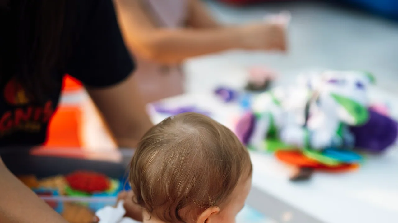 Un enfant joue avec des jouets accompagné d'un adulte dans un espace de jeu intérieur