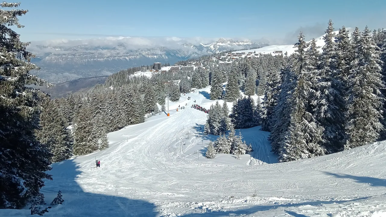 Piste enneigée et sapins de Chamrousse avec le secteur du Recoin vu depuis Roche Béranger en février 2022