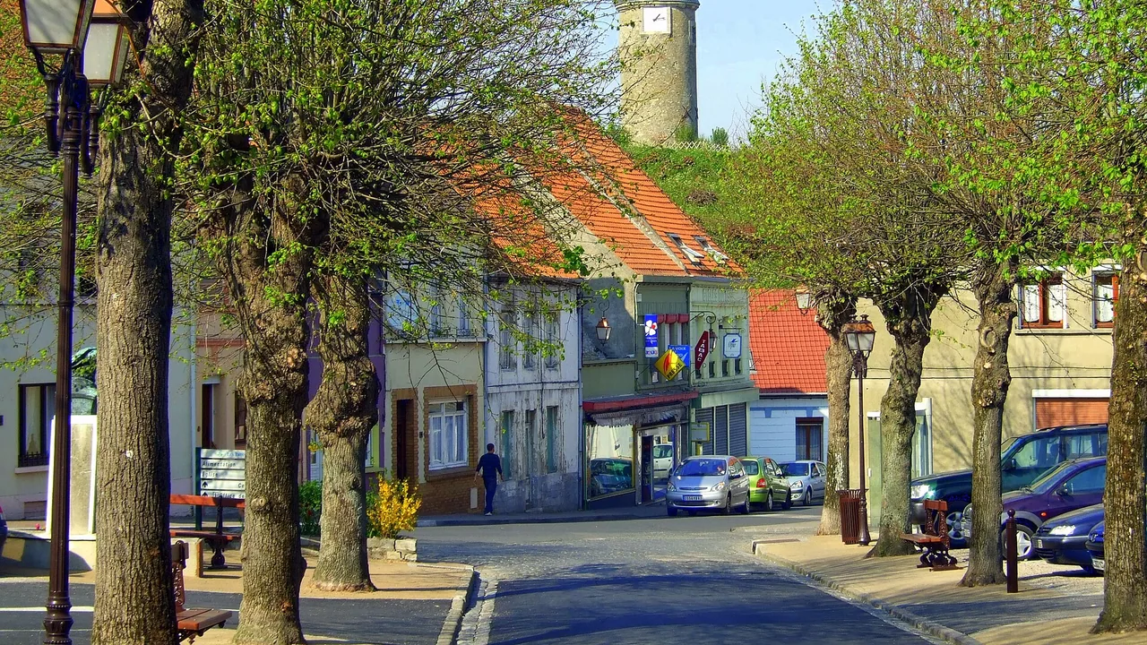 Tour de l'Horloge de Guînes dominant les toits derrière la place des Tilleuls
