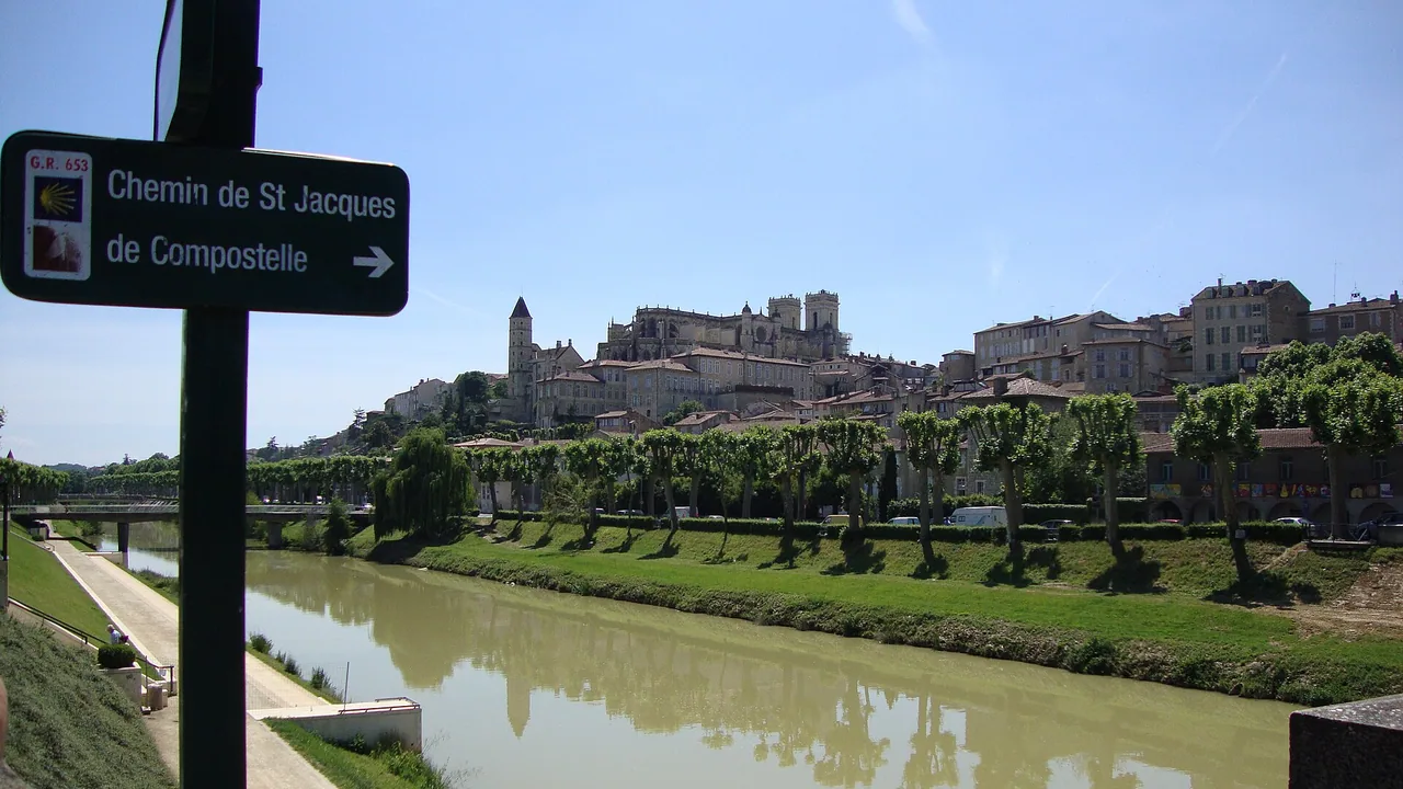 Vue d'Auch et de sa cathédrale depuis les berges du Gers, avec un panneau du chemin de Saint-Jacques au premier plan.